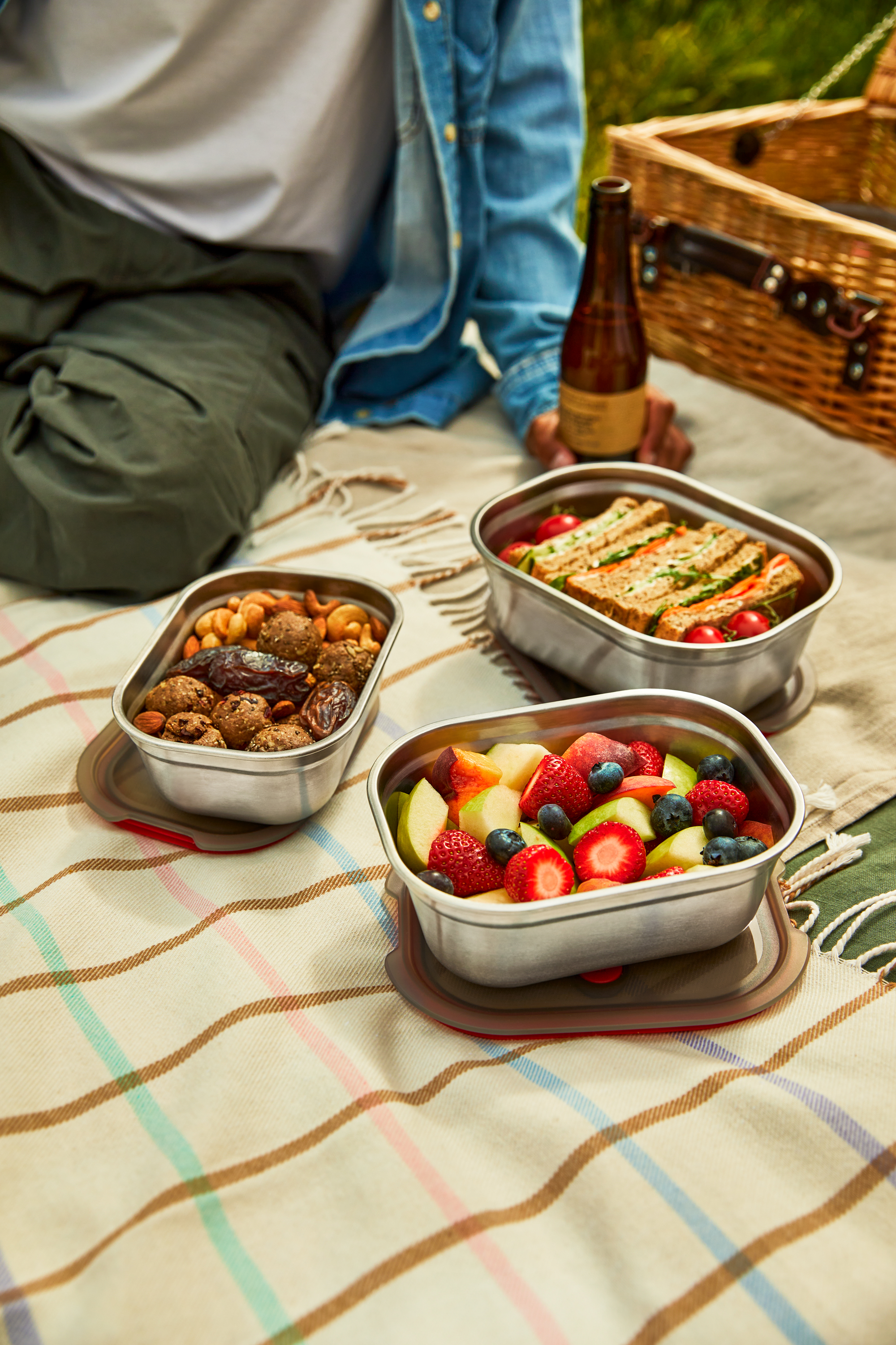 Black-blum meal prep boxes filled with fruit, sandwiches, and local snacks, packed and ready for a hike on Stanage Edge in the Peak District.